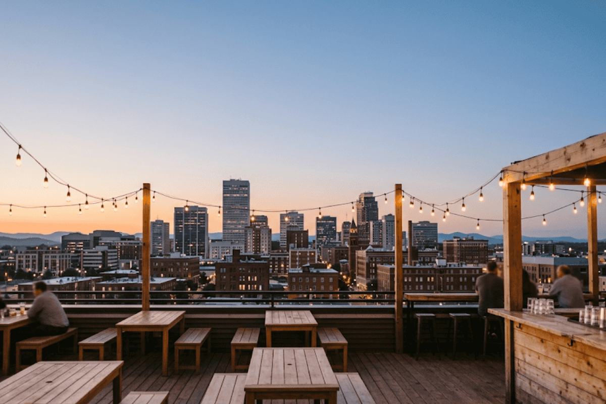 Rooftop bar tables under string lights at dusk with the Tulsa skyline at Roof Sixty-Six