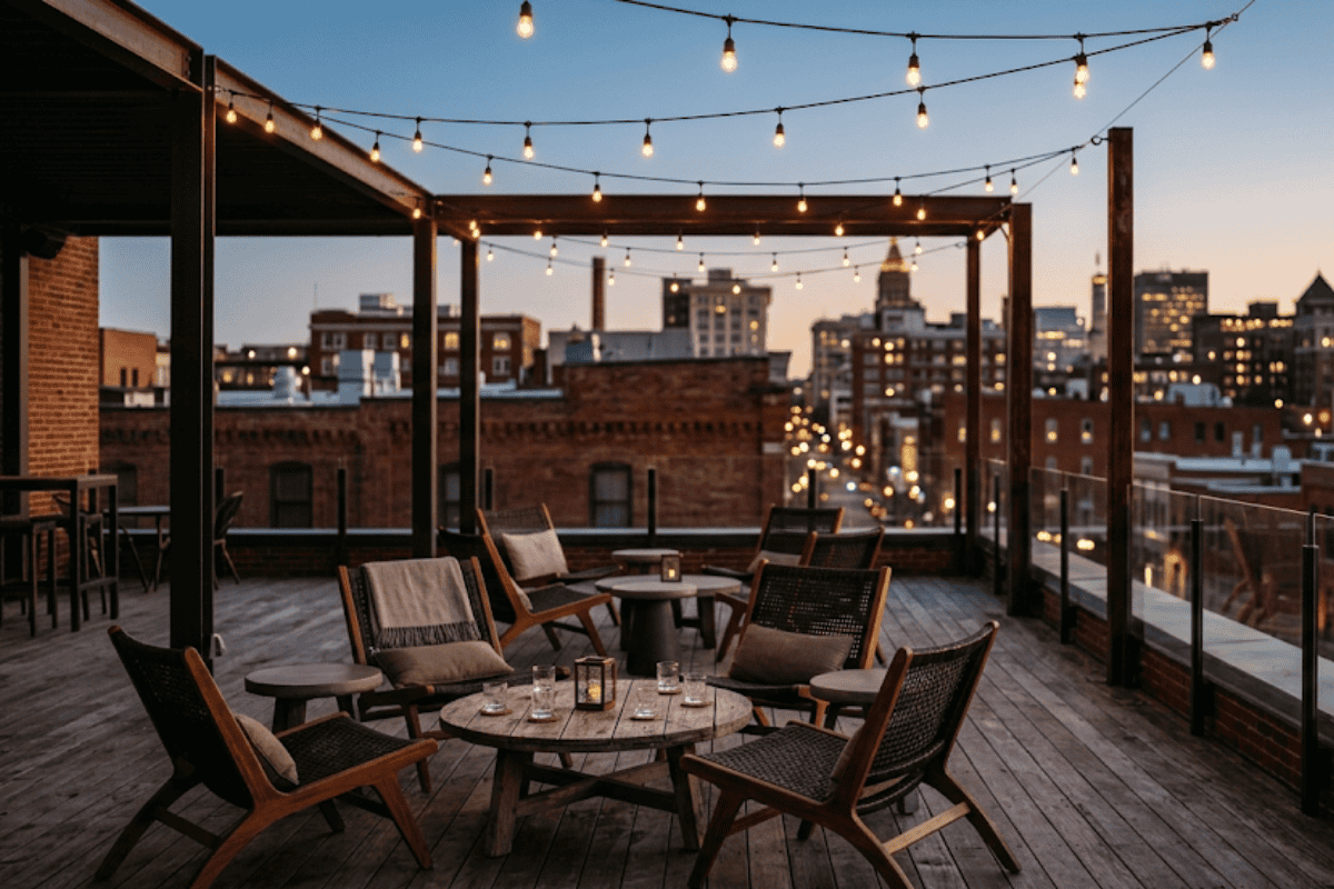 Rooftop bar lounge chairs and tables under string lights with a Tulsa skyline view